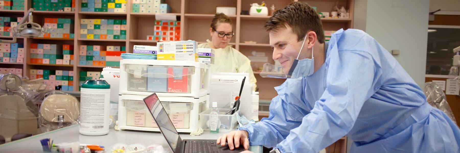 A dentistry faculty member works on his laptop in a lab.