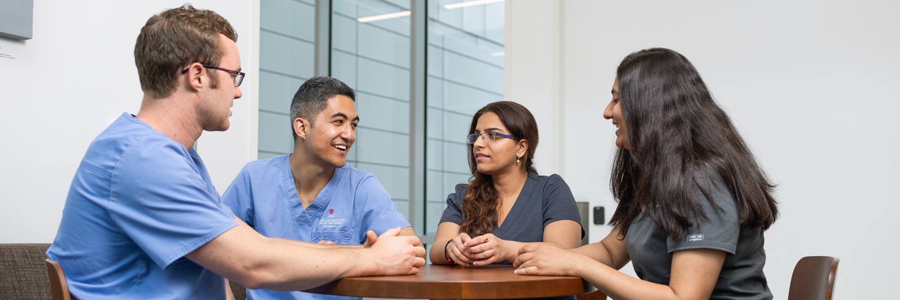 Dentistry professionals chat at a table.