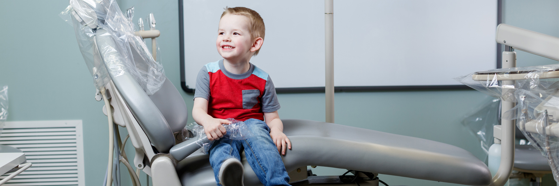 A small boy sits in an exam chair.