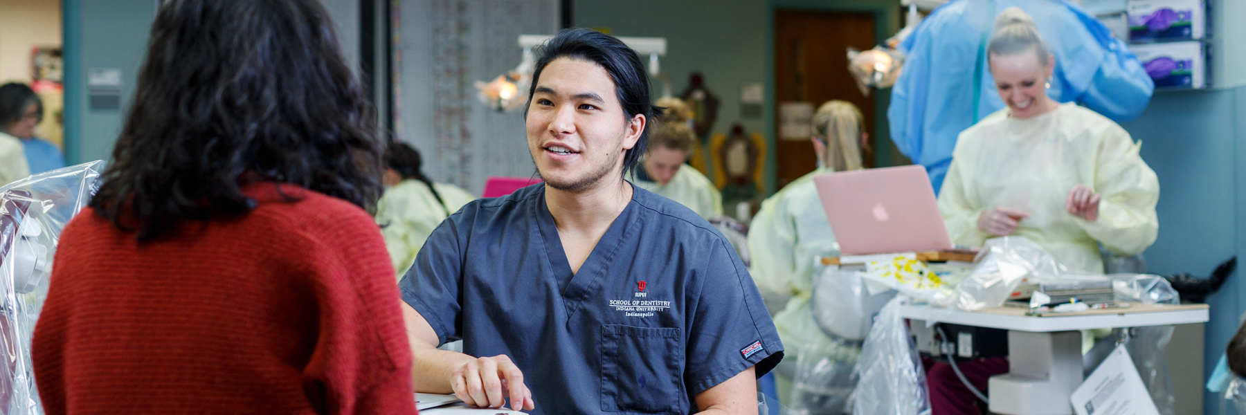 Dentistry students talk and practice in exam areas in a lab.